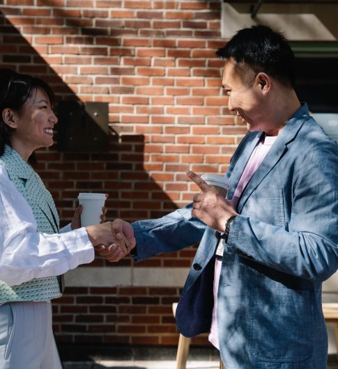 Two business colleagues shaking hands in a friendly outdoor meeting.